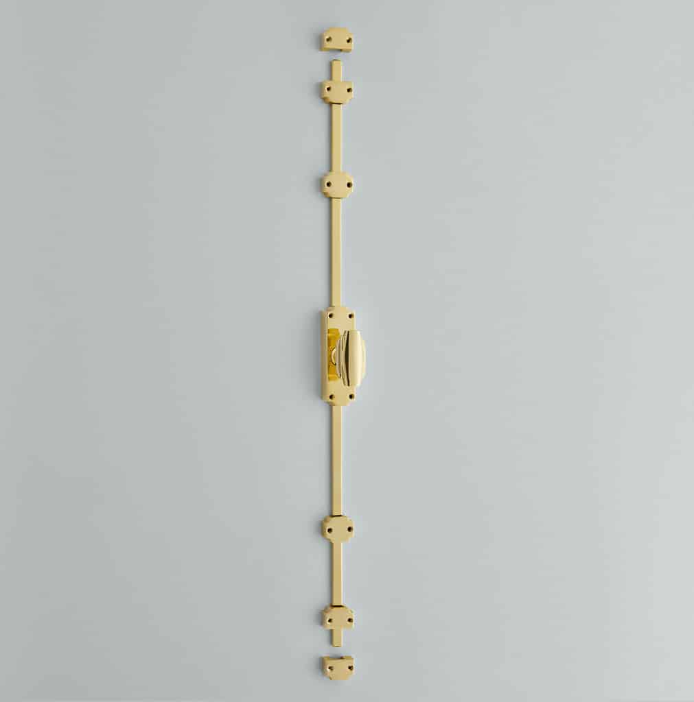 6001_s Vertical gold metal strip mounted on a gray wall with multiple bracket-like blocks and a central rotary switch/joint in the middle