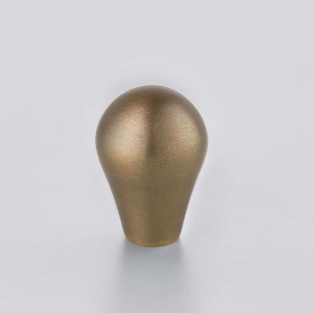 EB Horton Brasses Gold metallic lightbulb shaped sculpture on a white surface against a pale background
