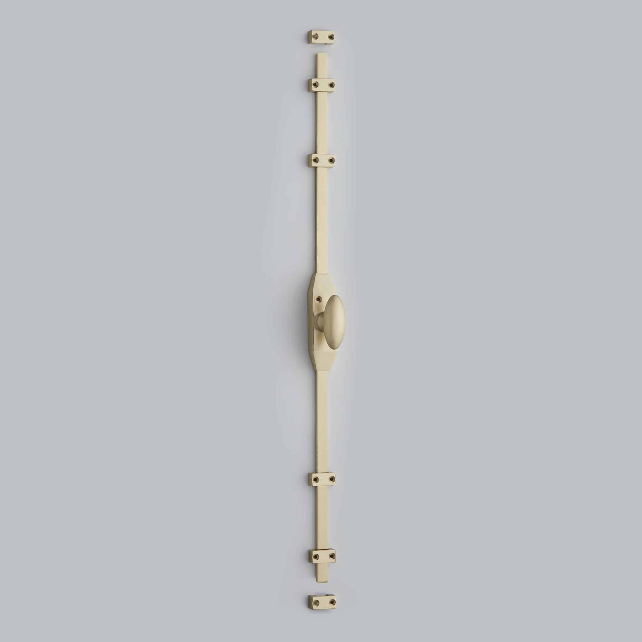 Satin Brass_01 Vertical beige wooden strip with square hinge blocks attached at intervals on a light gray wall, forming a linear mechanical assembly.