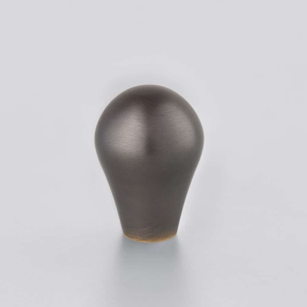 carnon Horton Brasses Dark bulb shaped object standing upright on a pale surface