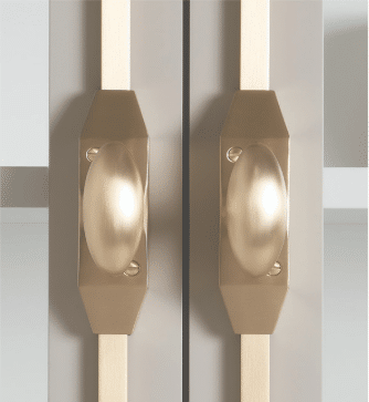 Close up of two brass door handles on a pair of light colored doors
