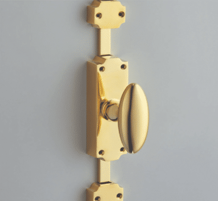 Polished brass door knob with rectangular backplate on a light gray door