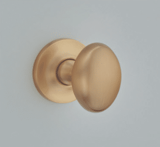 Brass door knob with round backplate mounted on a light gray wall