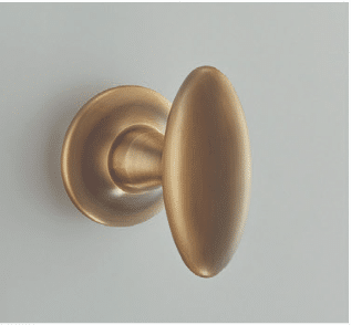 Brass door knob with round backplate on a light gray wallbackground on a door edge