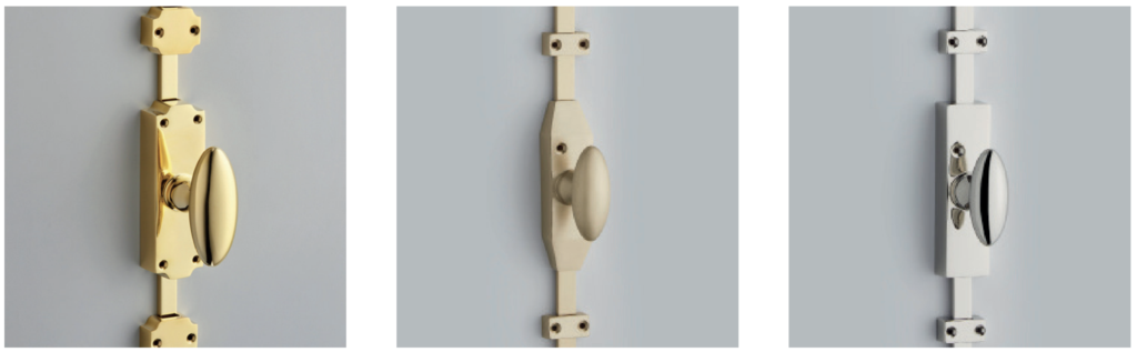 Gold finish vertical door knob on a rectangular backplate with mounting screws against a gray wall shown in a left panel style variation