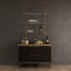 Modern dark wood sideboard with copper-framed glass shelves above, holding glassware and a wine bottle against a charcoal wall.