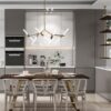 Contemporary kitchen with marble counters and island, a six-seat dining table under a brass starburst chandelier.