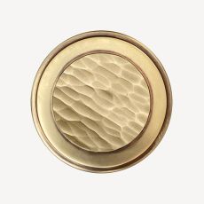 Brass round door knob with a textured hammered center on a white background