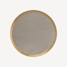 Round wall mirror with a thin gold frame on a pale background